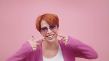 Çekici orta yaşlı, kızıl saçlı, beyaz dişlerini gösteren bir kadın.