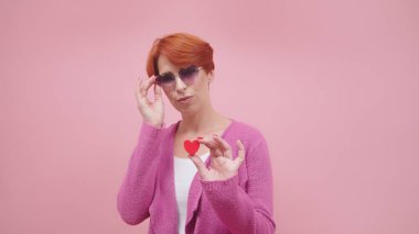 Orta yaşlı kızıl saçlı, kalp şeklinde bir kadın. Mor arkaplanda izole