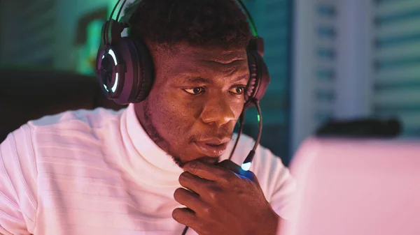 Feliz joven negro con auriculares iluminados usando el ordenador portátil. Oficina en el hogar y concepto de trabajo remoto. Retrato del comerciante de acciones —  Fotos de Stock