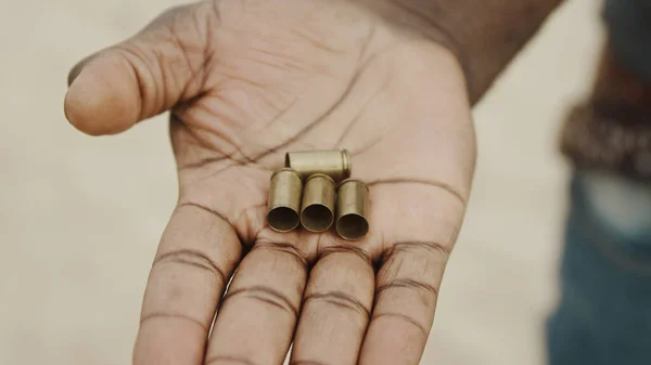 De cerca, manos negras contando balas usadas. Muchos casos de bala transferidos de una mano a otra —  Fotos de Stock