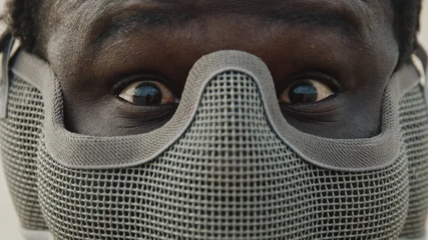 Крупный план, африканский человек в маске на лице и красные удивленные или испуганные глаза — стоковое фото