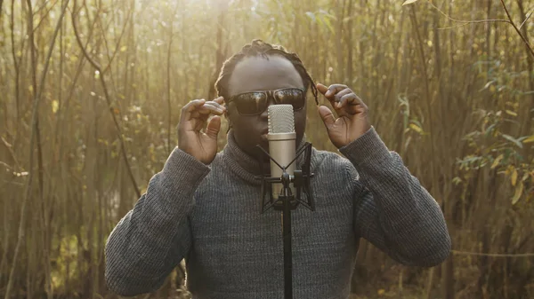 Jonge affricaanse man zingt in de natuur, zonnestralen door de bomen — Stockfoto