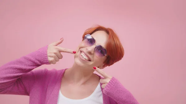 Mulher de meia-idade atraente com cabelo vermelho apontando dedos em seus dentes brancos — Fotografia de Stock