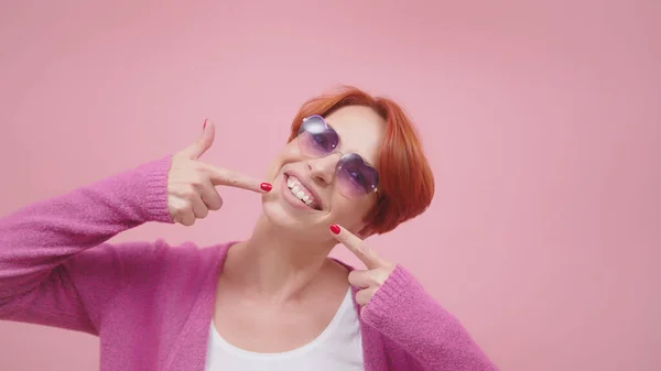 Attraktive Frau mittleren Alters mit roten Haaren, die mit den Fingern auf ihre weißen Zähne zeigen — Stockfoto