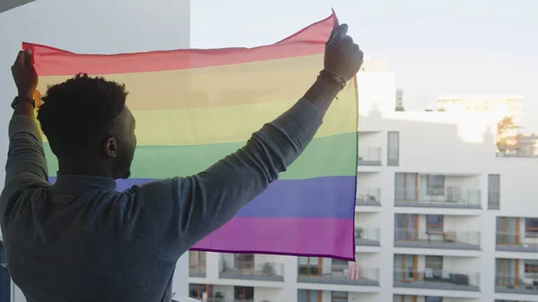 Jonge knappe homoseksuele zwarte man met regenboog vlag op het balkon — Stockfoto