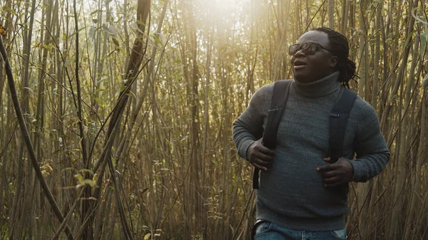Joven afroamericano negro viajero con mochila caminando por el bosque —  Fotos de Stock