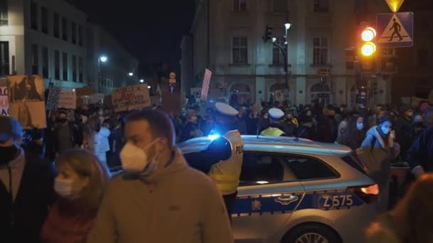 Varšava, Polsko 30.10.2020 - Protest proti potratům a lidským právům, stávka žen, demonstranti projíždějící kolem policejního auta osvětleného pohotovostním světlem — Stock video