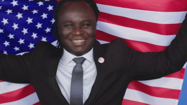 Portre, siyah üniformalı genç Afrikalı Amerikalı adam. Göğsünde ABD bayrağı var.