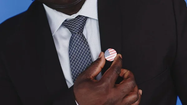 De cerca, hombre negro afroamericano en desgaste formal sosteniendo insignia de EE.UU.. — Foto de Stock