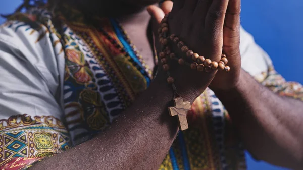 Hombre negro africano irreconocible en traje tradicional con rosario rezando con las manos sobre el pecho —  Fotos de Stock