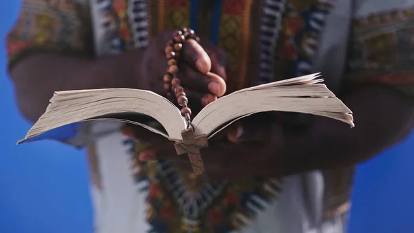 Unerkennbarer afrikanischer Schwarzer in traditioneller Kleidung mit Rosenkranz beim Lesen der Heiligen Bibel — Stockfoto