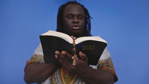 Portrét afrického černocha v tradičních šatech s růžencem čtení Bible svaté — Stock fotografie