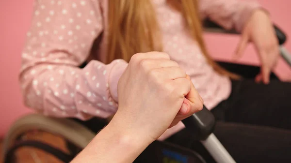 Aide soignante tenant la main d'une jeune femme handicapée en fauteuil roulant — Photo