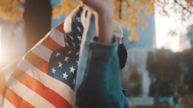 Parkta yüz maskesi ve Amerikan bayrağıyla dans eden beyaz bir kadın. Seçim 2020