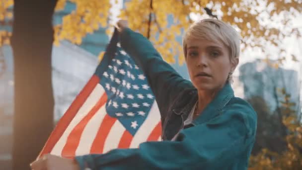 Trots serieuze jonge blanke vrouw dansen met Amerikaanse vlag in het park — Stockvideo