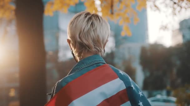 Young proud woman with face mask spinning with the usa flag over the shoulders — Stock Video