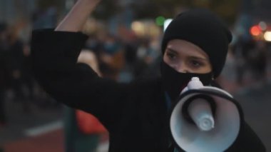 Tıbbi maskeli genç bir kız hoparlörden konuşuyor. Kürtaja karşı protesto, kadınları koruma hakkı