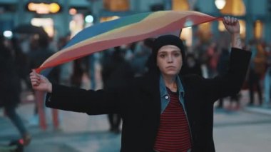 Protestodaki genç kadın elinde gökkuşağı gurur bayrağı tutuyor. Eşit haklar için gösteriler ve talep