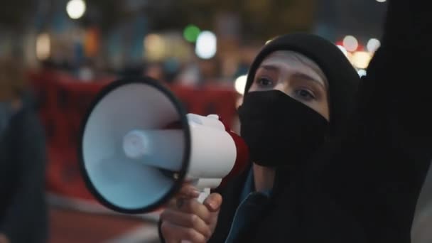 Demonstrationer mot inlåsningsåtgärder enligt covid-19. Ung kvinna med ansiktsmask skriker in i högtalaren — Stockvideo