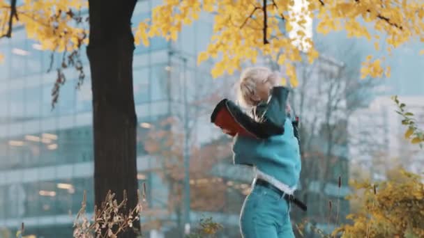 Tânără femeie caucaziană fericită în jachetă de piele sărind și filând în parc în ziua de toamnă — Videoclip de stoc