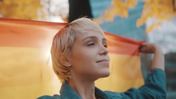 Femeie tânără beutiful cu păr scurt de ridicare steag curcubeu din capul ei în aer — Videoclip de stoc
