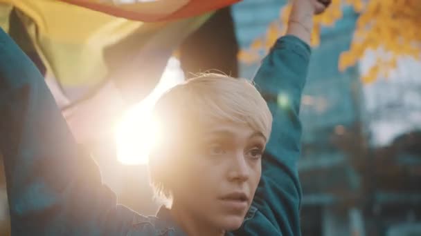 Schöne junge Frau mit kurzen Haaren schwenkt Regenbogenfahne im Park — Stockvideo