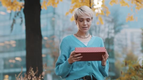 Mooie jonge Kaukasische vrouw geven de rode geschenkdoos met gouden strik — Stockvideo