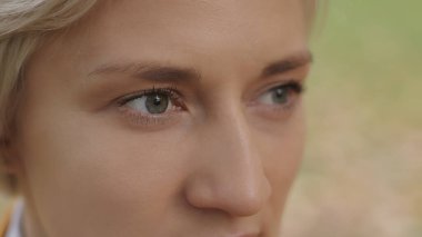 Kapatın. Parktaki genç, beyaz, sarışın kadının yeşil gözleri.