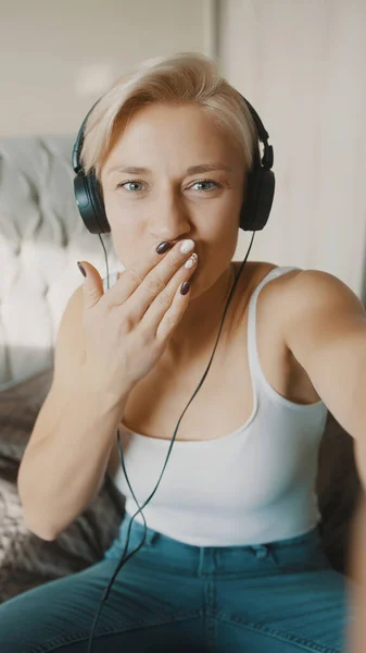 Mujer rubia joven con auriculares que tiene videollamada con amigos o familiares — Foto de Stock