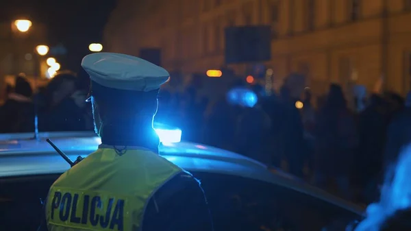 Varsovia, Polonia 30.10.2020 - Protesta contra el aborto y los derechos humanos, huelga de mujeres, manifestantes que pasan cerca de un coche de policía iluminado por la luz de emergencia — Foto de Stock