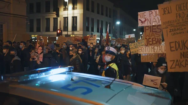 Varsovie, Pologne 30.10.2020 - Manifestation contre l'avortement et les droits humains, Grève des femmes, Des manifestants passent près d'une voiture de police éclairée par la lumière d'urgence — Photo