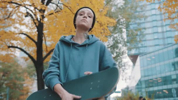 Adolescente rebelde, niña, sosteniendo el scateboard en el parque de la ciudad en otoño — Vídeo de stock