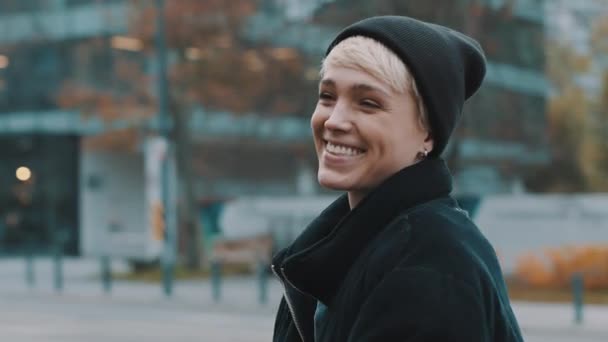 Porträt einer jungen lächelnden Frau mit schwarzem Hut und Winterjacke in der Stadt — Stockvideo