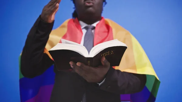 エレガントなスーツの虹の旗を手に聖書を持つアフリカ系アメリカ人黒人男性。ゲイ結婚の概念 — ストック写真