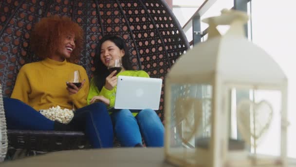 İki kadın gülüyor, dizüstü bilgisayarda film izleyen lezbiyen çift kırmızı şarap ve patlamış mısırla. — Stok video