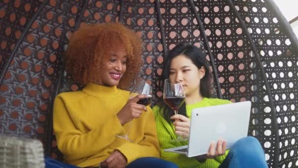 Dos mujeres chismeando en el columpio. Pareja lesbiana relajándose y bebiendo vino tinto. De cerca. — Vídeos de Stock