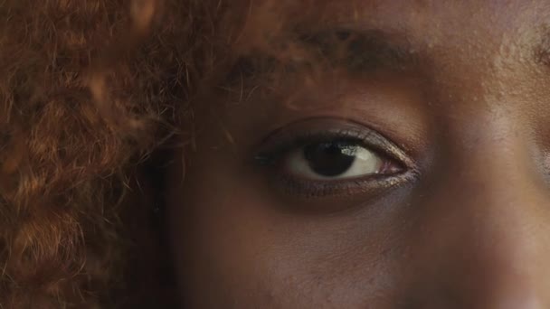 Close-up, oog van een Afrikaans amerikaanse jonge vrouw openen en kijken naar de camera — Stockvideo