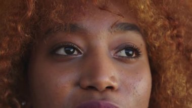 Kapatın. Ağır çekimde yanıp sönen genç siyahi kadının gözleri. Aşağı, yukarı, yana ve kameraya bakıyorum.. 