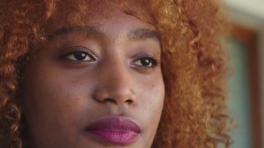 Kıvırcık saçlı ve pembe rujlu Afrikalı Amerikalı siyahi bir kadının portresi.