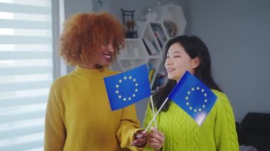 Çok ırklı dostluk ve eşitlik. Avrupa Birliği bayrağı taşıyan Afrikalı Amerikalı ve Asyalı kadın. Öğrenci değişim programı