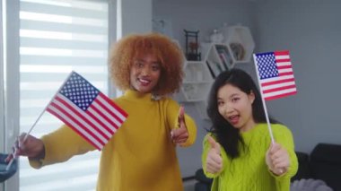 Çok ırklı dostluk ve öğrenci değişim programı. Afro-Amerikalı ve Asyalı kadın ABD bayraklarını tutuyor. 
