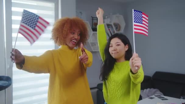 Amizade multirracial e programa de intercâmbio de estudantes. Africano americano e asiático mulher segurando EUA bandeiras. — Vídeo de Stock