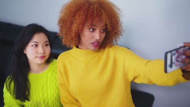 Meilleurs amis Asiatique et afro-américaine femme noire prenant selfie à l'aide d'un smartphone. Des visages drôles — Video