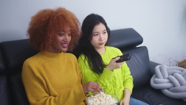 Çok ırklı dostluk. Afgan Amerikalı siyah ve Asyalı kadın patlamış mısır yiyor ve film seyrediyor. — Stok video