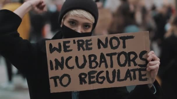 Womens march. Young woman with face mask protesting with banner sign - We are not incubators to regulate. protest against strict abortion laws — Stock Video