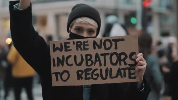 Les femmes marchent. Jeune femme avec masque facial protestant avec signe de bannière - Nous ne sommes pas des incubateurs à réguler. protestation contre les lois strictes sur l'avortement — Video