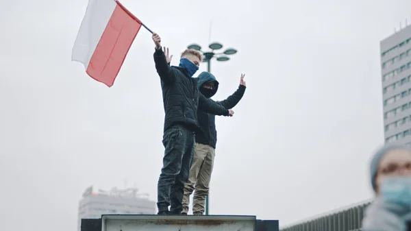 Warsaw, Poland 11.11.2020 - Independence day march on 102nd anniversary in Warsaw. Two young man waving polish flag — Stock Photo, Image