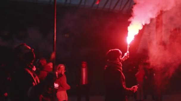 Βαρσοβία Πολωνία 11.11.2020 - Οι συμμετέχοντες στην πορεία ανεξαρτησίας κρατούν πολωνική σημαία και καίνε κόκκινες φωτοβολίδες — Αρχείο Βίντεο