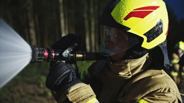 Retrato del bombero rociando fuego con la manguera. De cerca. —  Fotos de Stock