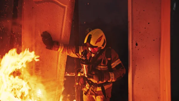 Пожарный входит через дверь горящего дома. — стоковое фото